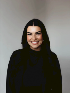 A woman with long dark hair smiling at the camera.